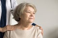 Older woman looking into distance, therapist touch shoulders supporting patient Royalty Free Stock Photo