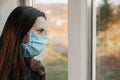 Close up of portrait upset young woman look far in window thinking about troubles, sad female in medical sterile face mask Royalty Free Stock Photo