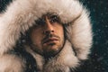 Close up portrait of a white man dressed with an eskimo jacket in the snow