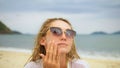 Close-up portrait woman apply sun cream protection lotion. Young woman on beach near sea applying sunscreen. Pretty Royalty Free Stock Photo