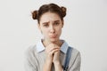 Close up portrait woman with brown hair in double buns pouting with pity look holding hands like praying. Pathetic