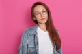 Close up portrait of woman with dark staright hair, wearing denim jacket, white t shirt and spectacles, standing over rosy Royalty Free Stock Photo