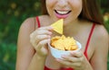 Close up portrait of woman eating tortilla chips with a full bowl in her hand