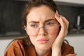 Close up portrait of woman in glasses with concerned, sad face, looking upset, troubled expression, sitting at home