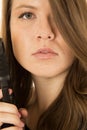 Close-up portrait of a woman holding a pistol with a serious exp