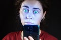 Close up portrait of a woman looking at her mobile phone like a zombie. Black background. The concept of online addiction Royalty Free Stock Photo