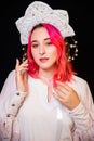 Close-up portrait of a woman with pink hair in a white dress with a kokoshnik on her head posing isolated on a black background Royalty Free Stock Photo