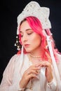 Close-up portrait of a woman with pink hair in a white dress with a kokoshnik on her head posing isolated on a black background Royalty Free Stock Photo