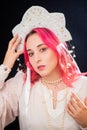 Close-up portrait of a woman with pink hair in a white dress with a kokoshnik on her head posing isolated on a black background Royalty Free Stock Photo