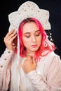 Close-up portrait of a woman with pink hair in a white dress with a kokoshnik on her head posing isolated on a black background Royalty Free Stock Photo