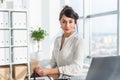 Close-up portrait of a woman sitting in modern loft office, smiling, looking at camera. Young confident female business Royalty Free Stock Photo