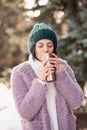 Young woman walking on winter day, holding travel stainless Steel mug with hot coffee. reusable water bottle.