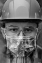 Close-up portrait of a worker in a helmet, mask and goggles among smoke and exhaust pipes. double exposure.