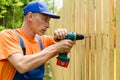 Close up portrait of worker, mounting wooden fence