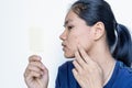 Close-up portrait of a worried young Asian woman in front of small mirror with on white background. Royalty Free Stock Photo