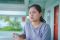 Close-up portrait of worried young woman standing thinking alone in front of her room.