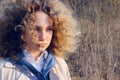 Close up portrait of a youg girl looking to the side. Cute curly girl outdoor. People, travel concept.