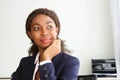 Close up portrait of young african businesswoman sitting at her desk looking away and thinking Royalty Free Stock Photo