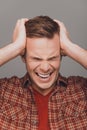 Close up portrait of young angry furios man toucing his head