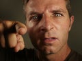 Close up portrait of young angry and upset man pointing with finger as if scolding and blaming you in rage feeling rageful showing Royalty Free Stock Photo