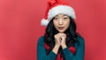 close up portrait of young asia woman with long hair wearing santa hat posing make a wish isolated over red background. Emotion Royalty Free Stock Photo