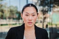 Close up portrait of young asian business woman or executive looking serious at camera wearing a suit standing at Royalty Free Stock Photo