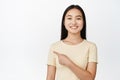 Close up portrait of young asian female student pointing left, smiling happy and showing logo, company banner aside Royalty Free Stock Photo