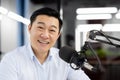 Close-up portrait of a young Asian man sitting in the office in front of a microphone and smiling at the camera Royalty Free Stock Photo