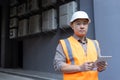 Close-up portrait of a young Asian man wearing a hard hat and vest, standing outside a factory, construction site Royalty Free Stock Photo