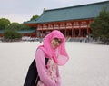 Close up portrait of young Asian muslim woman wearing hijab and eyeglasses in court yard of shrine in Japan looking at camera Royalty Free Stock Photo