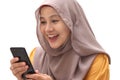 Close up portrait of young Asian muslim woman wearing hijab get good news on her phone, happy surprised expression Royalty Free Stock Photo