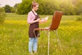 Close up portrait of young attractive artist in open air, being good at oil painting. Cute lady drawing landscape, likes to Royalty Free Stock Photo
