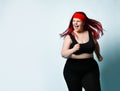 Young attractive plus-size model with flowing red hair, squinted eyes and naughty toothy smile on blue background. Copy space