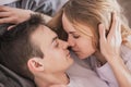 Close up portrait of young attractive romantic couple hugging and kissing, laying down on a bed, being loving with each other. Royalty Free Stock Photo