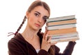 Close up portrait of young attractive student girl in brown sport clothes with a lot of books in hands isolated on white Royalty Free Stock Photo