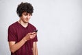 Close up portrait of young attractive teenager with dark crisp hair. Guy listens to music or watches video from his smart phone. Royalty Free Stock Photo