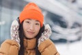 Close-up portrait of a young beautiful Asian woman looking at the camera and smiling while listening to music with big headphones Royalty Free Stock Photo