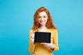 Close up Portrait young beautiful attractive redhair girl smiling showing digital tablet screen on black. Blue Pastel Royalty Free Stock Photo