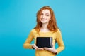 Close up Portrait young beautiful attractive redhair girl smiling showing digital tablet screen on black. Blue Pastel Royalty Free Stock Photo