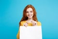 Close up Portrait young beautiful attractive redhair girl smiling with white shopping bag. Blue Pastel Background. Royalty Free Stock Photo