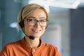 Close-up portrait of young beautiful blonde woman at workplace, call center worker smiling and looking at camera Royalty Free Stock Photo