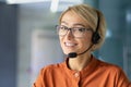 Close-up portrait of young beautiful blonde woman at workplace, call center worker smiling and looking at camera Royalty Free Stock Photo