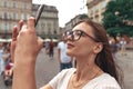 Close up portrait, young beautiful brunette girl in glasses making selfie in the center of the old city Royalty Free Stock Photo