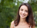 Close up portrait of young beautiful brunette woman with adorable smile enjoying sunlight in city park Royalty Free Stock Photo