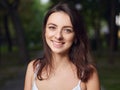 Close up portrait of young beautiful brunette woman with adorable smile enjoying sunlight in city park Royalty Free Stock Photo