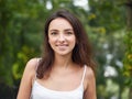Close up portrait of young beautiful brunette woman with adorable smile enjoying sunlight in city park Royalty Free Stock Photo