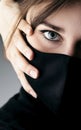 Close up portrait of young beautiful elegant woman in black mask and hand clasped her face on studio background, computer hacker,