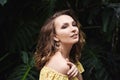 Close-up portrait of young beautiful girl with curly hair summer dress in tropical forest Royalty Free Stock Photo