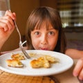 Close up portrait of young beautiful girl with funny facial expression eating cheesecakes for breakfast