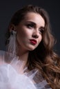 Close up portrait. Young beautiful girl with perfect make up in white veiling dress. Studio shot